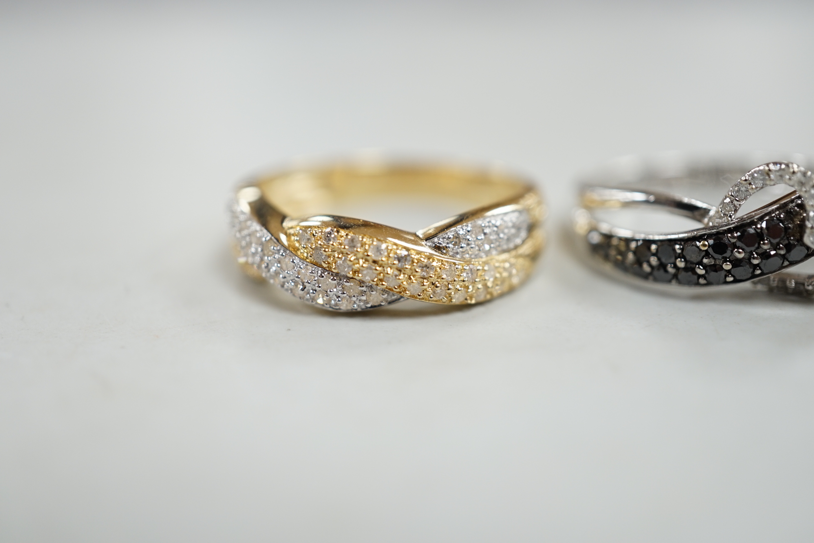 A modern 14k white metal and two colour diamond chip set heart motif crossover ring, size N/O and a similar two colour 14k and diamond chip cluster set crossover ring, size S, gross weight 6.8 grams.